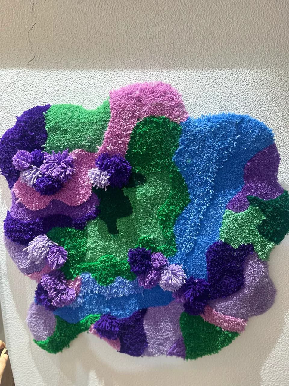 Multicoloured moss hand-tufted rug with varied textures and pom poms